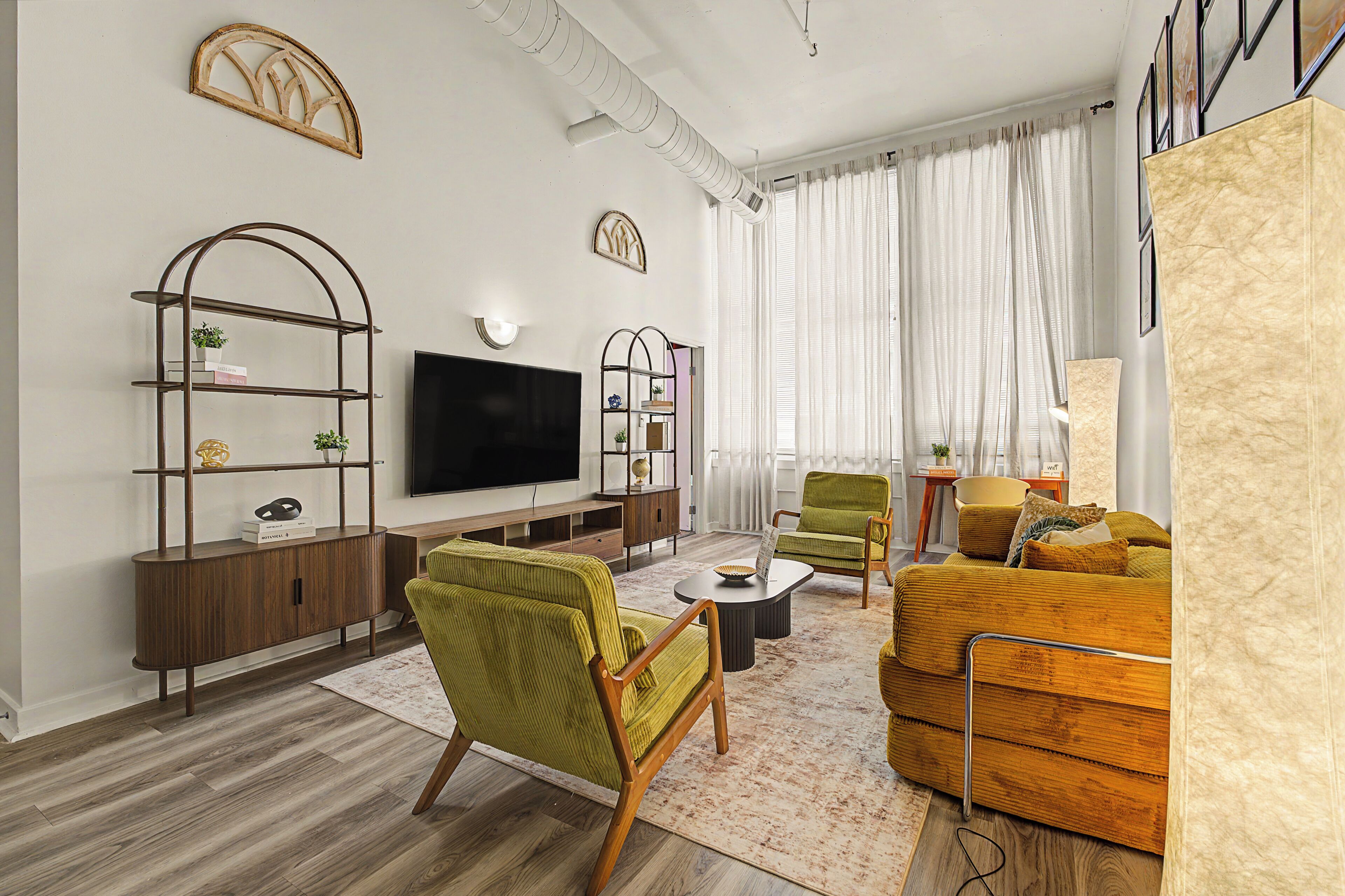 A modern living room with a flat-screen TV, wooden furniture, and decorative wall art.