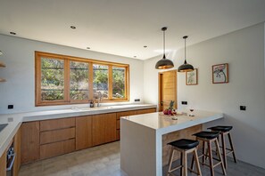 Eine moderne Küche mit Holdekor, einem großen Fenster und einer Kochinsel mit Barhocker.