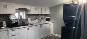 A kitchen with white cabinets, a microwave, a coffee maker, and a black refrigerator. - Your Windsor Home Away from Home | 3BR One-Storey (Windsor)