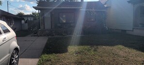 A residential area with a house, a parked car, and a grassy yard. - Your Windsor Home Away from Home | 3BR One-Storey (Windsor)