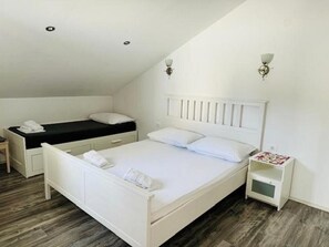 Een slaapkamer met een wit bed, een nachtkastje en een klein witte nachtkastje.