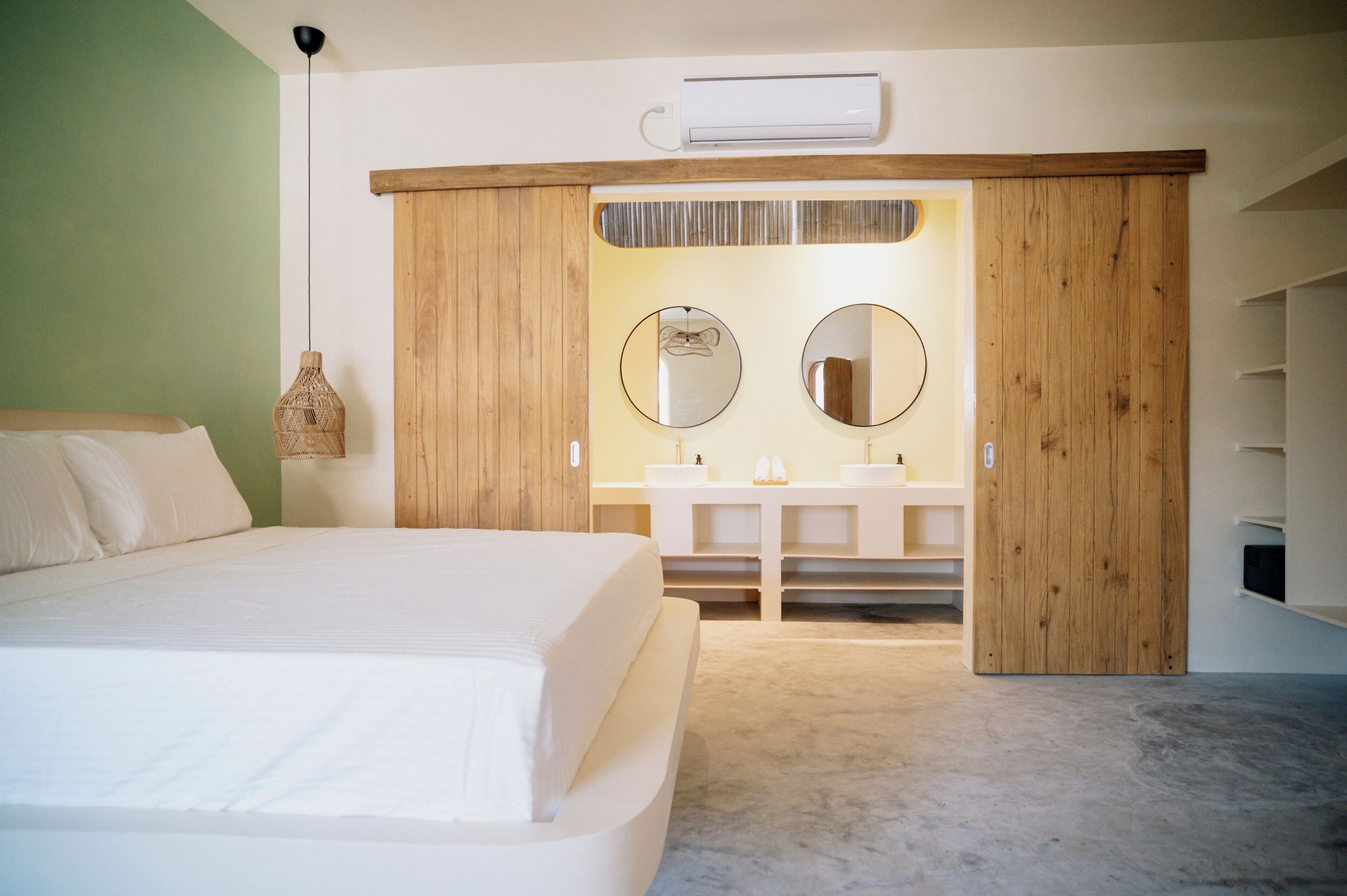 A bedroom with a bed, a vanity with mirrors, and a wardrobe.