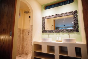 Un baño con ducha, dos lavamanos y un espejo decorativo.
