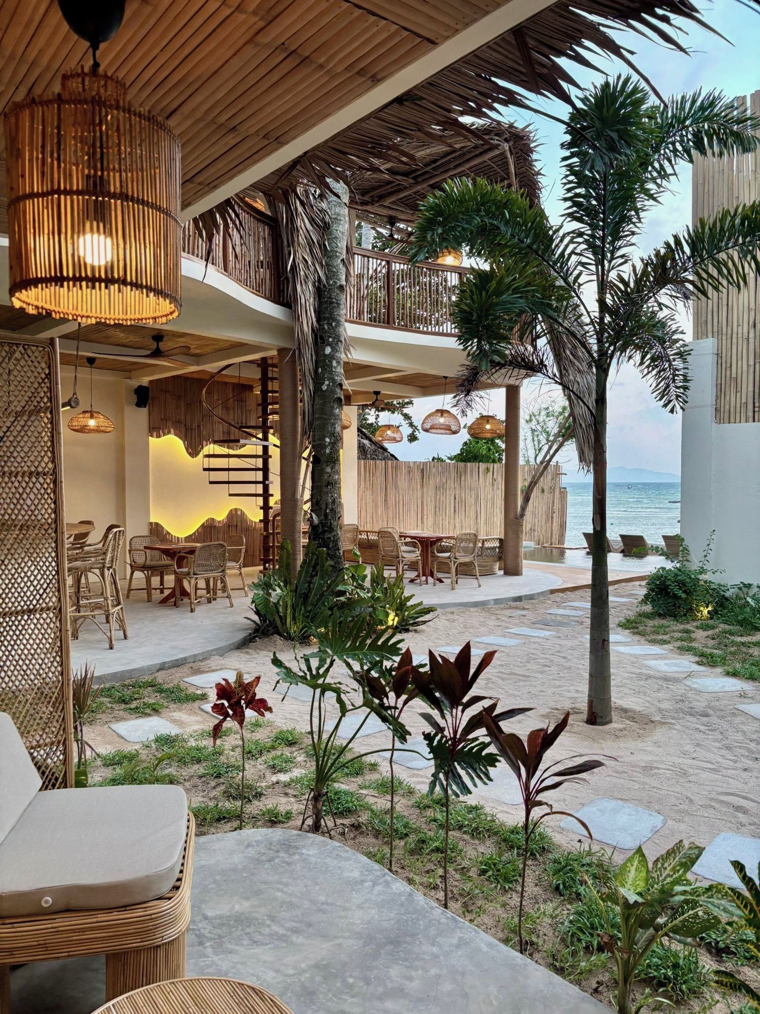 Un restaurante frente al mar con terraza, techo de madera y vistas al océano.