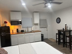 A compact kitchen with a microwave, sink, and cabinets. There is a dining area with a table and chairs. - Peaceful Private Pet Friendly Studio-10 Miles from Buc-ee's & I65 (Harvest)