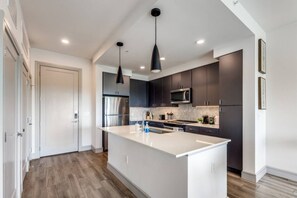 Una cocina moderna con una isla central, electrodomésticos de acero inoxidable y muebles oscuros.