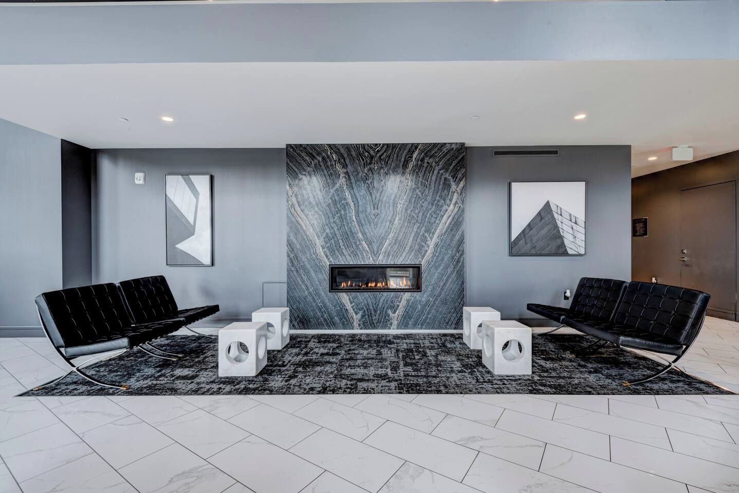Eine moderne Lobby mit Kamin, zwei schwarzen Sofas und einem gemusterten Teppich.