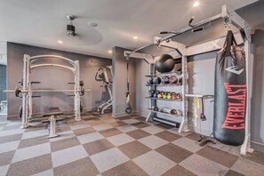 Un gimnasio con una estructura para sentadillas, mancuernas de concho y un saco de boxeo.