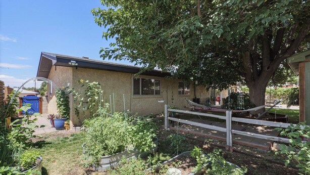 A residential property with a garden, a wooden fence, and a house with a sloped roof.