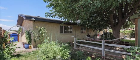 A residential property with a garden, a wooden fence, and a house with a sloped roof.