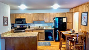 A kitchen with wooden cabinets, a black refrigerator, a microwave, and a coffee maker. - Perfect 1-bedroom condo, a 7 min walk to The Village (Mammoth Lakes)