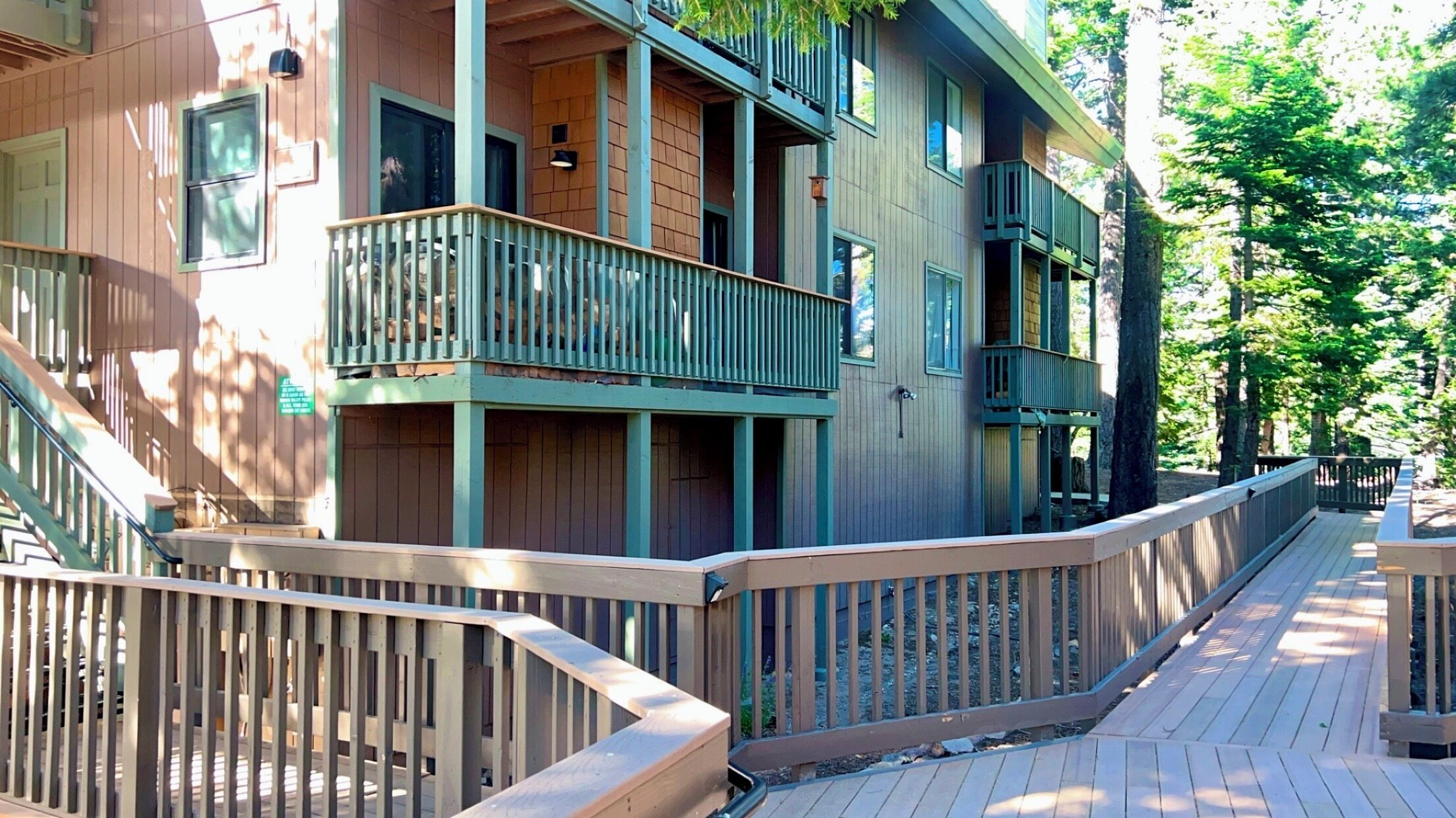 A multi-story building with balconies and a wooden deck.