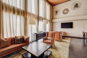 A spacious living room with a sofa, armchairs, a coffee table, and a TV mounted on the wall. - 2BD Pumpkin King Retreat |NRG & TMC| Pool & Patio (Houston)