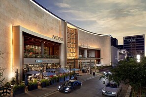 Un edificio moderno con un llamativo letrero de 'Nobu', zona de estar al aire libre y un restaurante 'Blanco'.