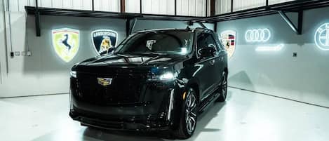 A black luxury SUV in a spacious, well-lit garage with high ceilings and metal walls.