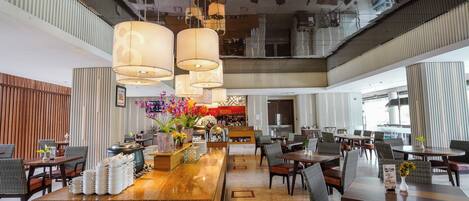A spacious hotel lobby with a central bar area, seating arrangements, and a modern ceiling design.