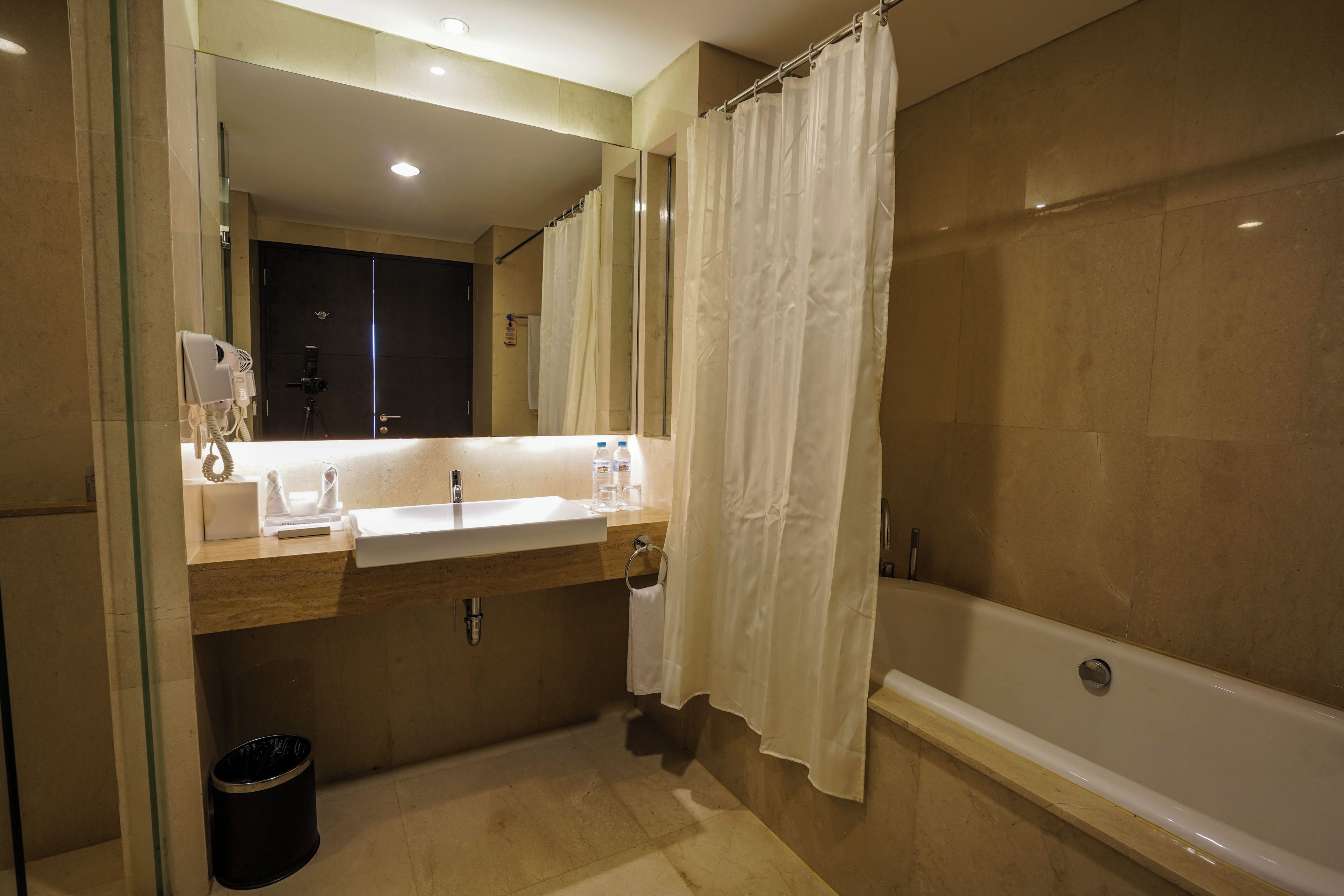A bathroom with a bathtub, a sink, a mirror, and a shower curtain.