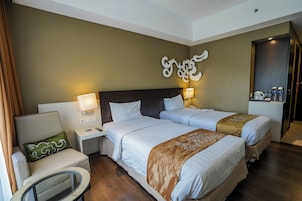 Habitación de hotel con dos camas, una mesita de noche, una silla y un adorno en la pared.