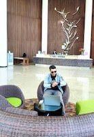A man sitting on a chair with a laptop in a lobby area with a reception desk labeled 'SOLL MARINA'.