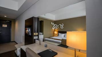 Una habitación de hotel con cama, mesita de noche, lámpara y televisor.