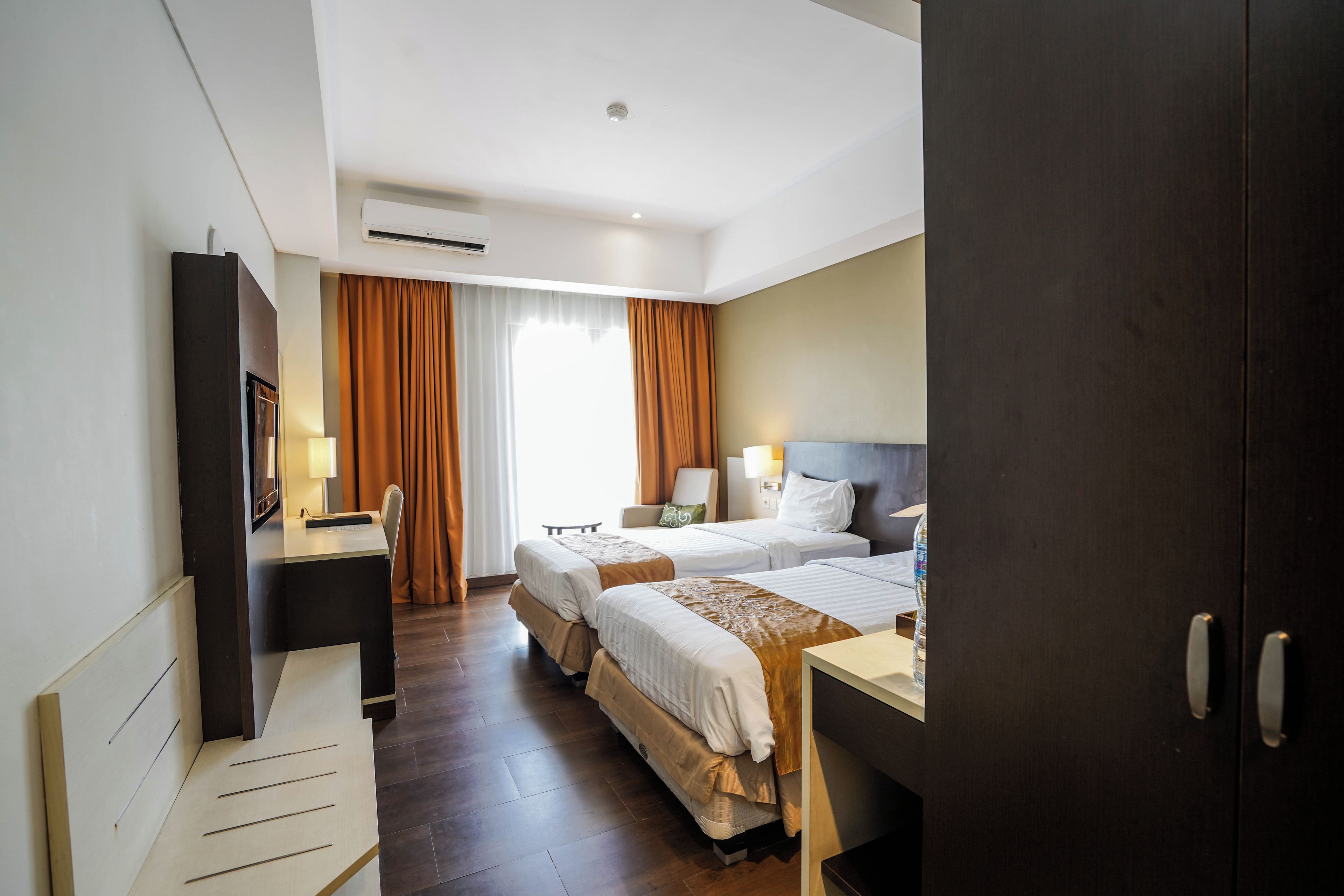 Habitación de hotel con dos camas, un escritorio, una silla, un televisor y un equipo de aire acondicionado.