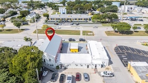 An aerial view of a commercial building with a parking lot, surrounded by greenery and a marina in the background. - Cozy 2-bedroom apartment with AC and kitchen, Tavernier (Tavernier)