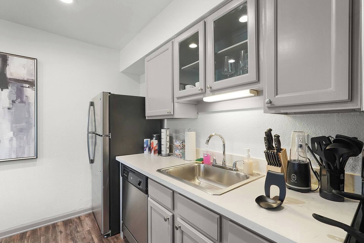 A modern kitchen with stainless steel appliances, a double sink, and a countertop with various utensils and a coffee machine.