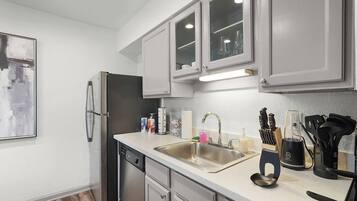 A modern kitchen with stainless steel appliances, a double sink, and a countertop with various utensils and a coffee machine.