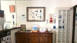 A reception area with a wooden cabinet, framed calligraphy, and various informational posters. - Vrbo Property (伊東市)