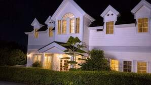 A large, white, two-story house with multiple windows and a well-lit entrance. - Vrbo Property (伊東市)