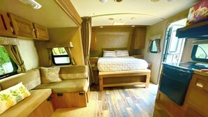 A compact RV interior with a kitchenette, a bed, and a seating area. - Surprisingly Comfy RV with Everything You Need (Jacksonville)