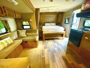 Interior compacto de motorhome com cozinha compacta, cama e área de estar.
