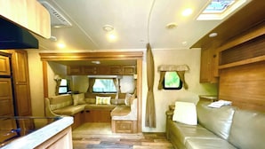 A compact RV interior with a kitchenette, a seating area, and a window. - Surprisingly Comfy RV with Everything You Need (Jacksonville)