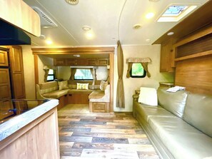 Interior compacto de motorhome com cozinha compacta, área de estar e janela.