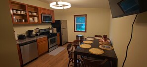 A compact kitchen with wooden cabinets, stainless steel appliances, and a dining table set with placemats.