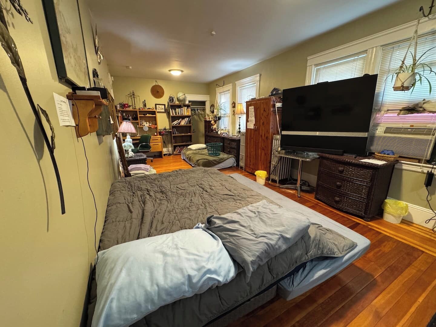 Quarto com cama, televisão, penteadeira e escrivaninha com cadeira.