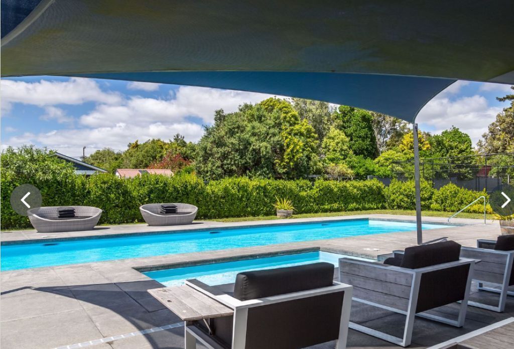 A swimming pool with lounge chairs and a shaded area.