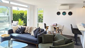 Ein modernes Wohnzimmer mit einer Couch, einem Glastisch und einer Essecke mit Stühlen und einem Tisch.