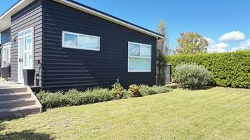 A modern two-story house with a dark exterior, a front porch, and a well-maintained lawn.