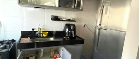A compact kitchen with a built-in microwave, a coffee maker, and a refrigerator.
