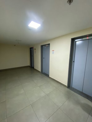 Un pasillo con tres puertas, una lámpara en el techo y suelo de baldosas.