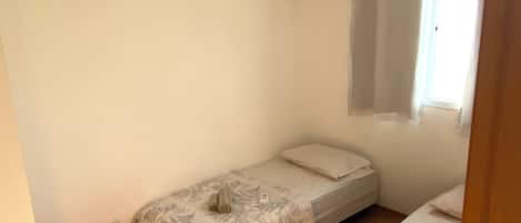 Un alojamiento pequeño y de una sola habitación, con cama, ventana con cortinas y aire acondicionado de pared.