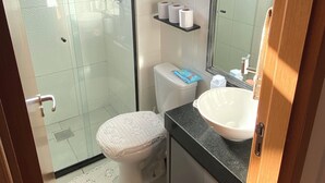 Ein Badezimmer mit Duschkabine, Toilette, Waschbecken und Spiegel.