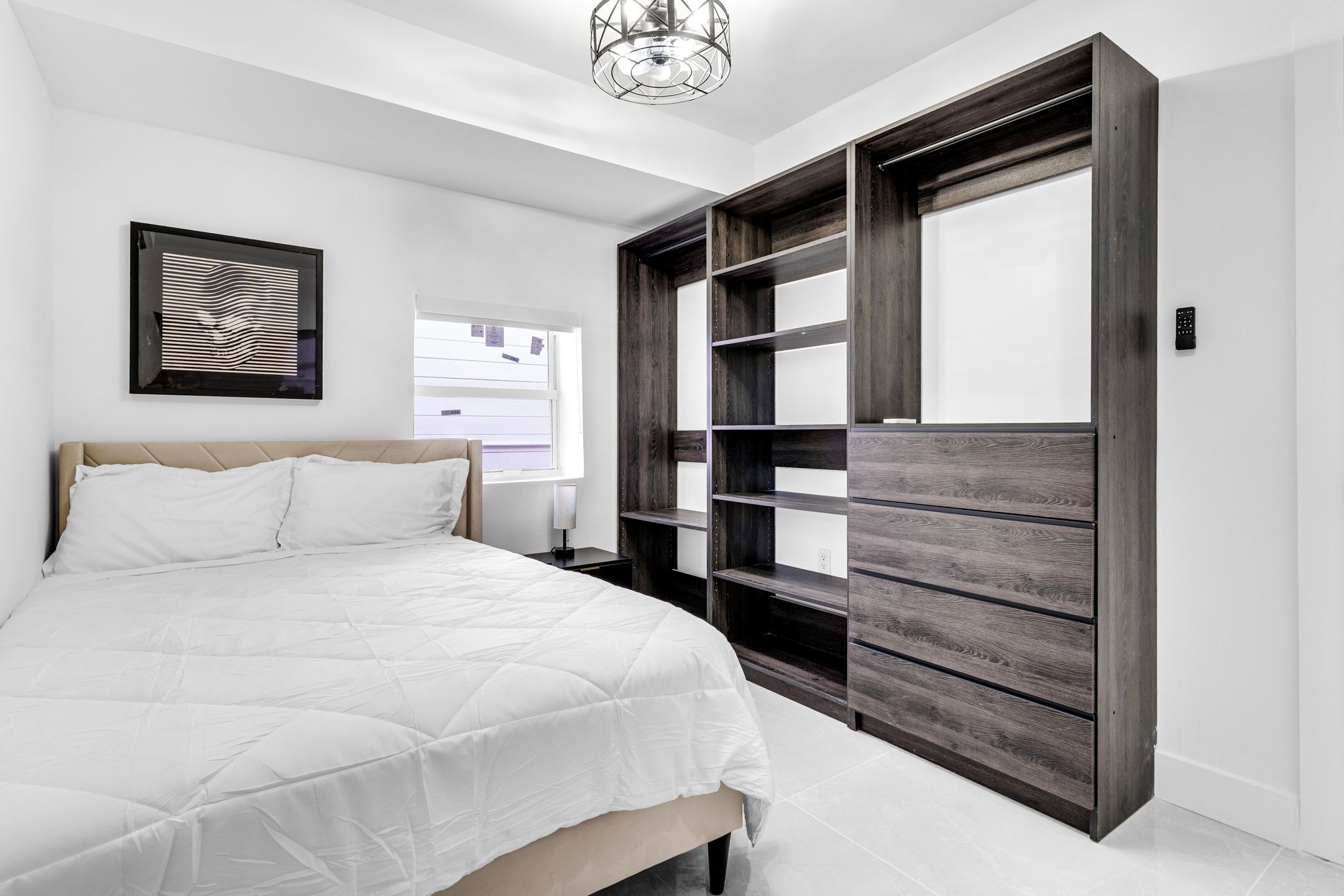 A bedroom with a bed, a large wardrobe, and a framed picture on the wall.