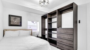 Un dormitorio con una cama, un armario grande y un cuadro enmarcado en la pared.