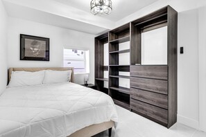 Una camera da letto con un letto, un'ampia armadio e un quadro appeso al muro.