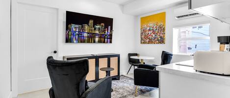 A modern kitchen with a white countertop, black chairs, and a dining area with a round table.