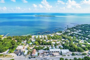 An aerial view of a coastal town with a marina, residential buildings, and a clear view of the ocean. - Adorable 1-bedroom apartment with AC and kitchen, Tavernier (Tavernier)