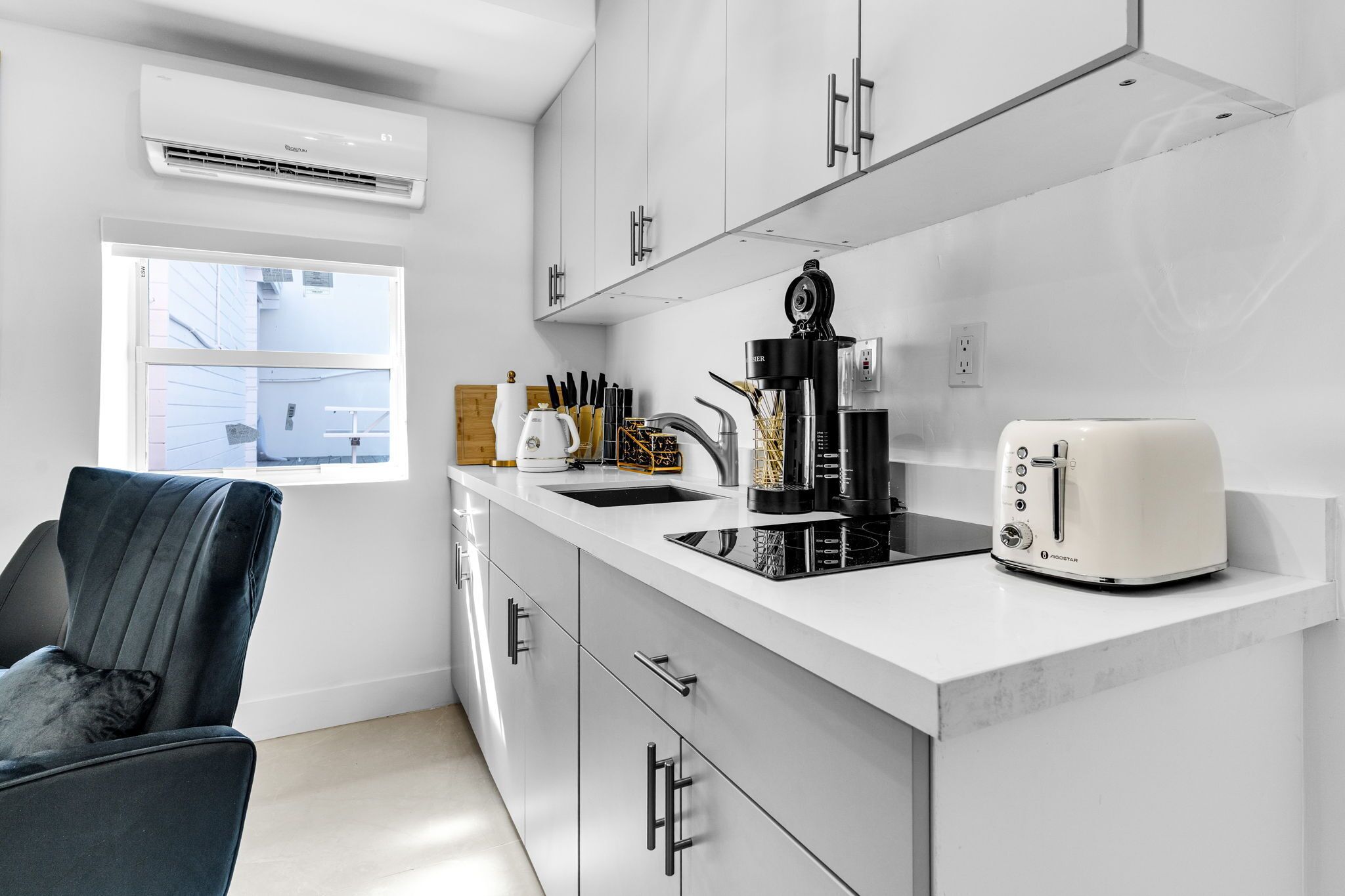 A modern kitchen with white cabinets, a black countertop, a toaster, and a coffee maker.