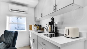 Una cocina moderna con armarios blancos, encimera negra, tostadora y cafetera.
